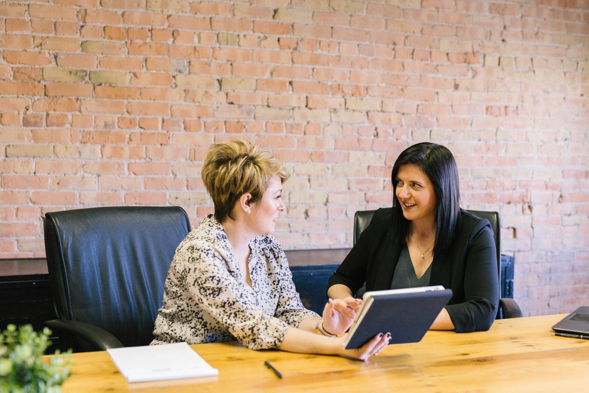 Two women sitting on chairs in front of table.