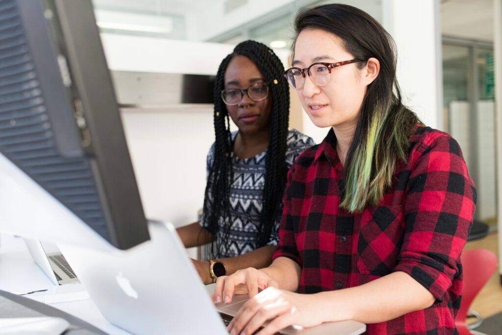 Two women talking in front of laptop