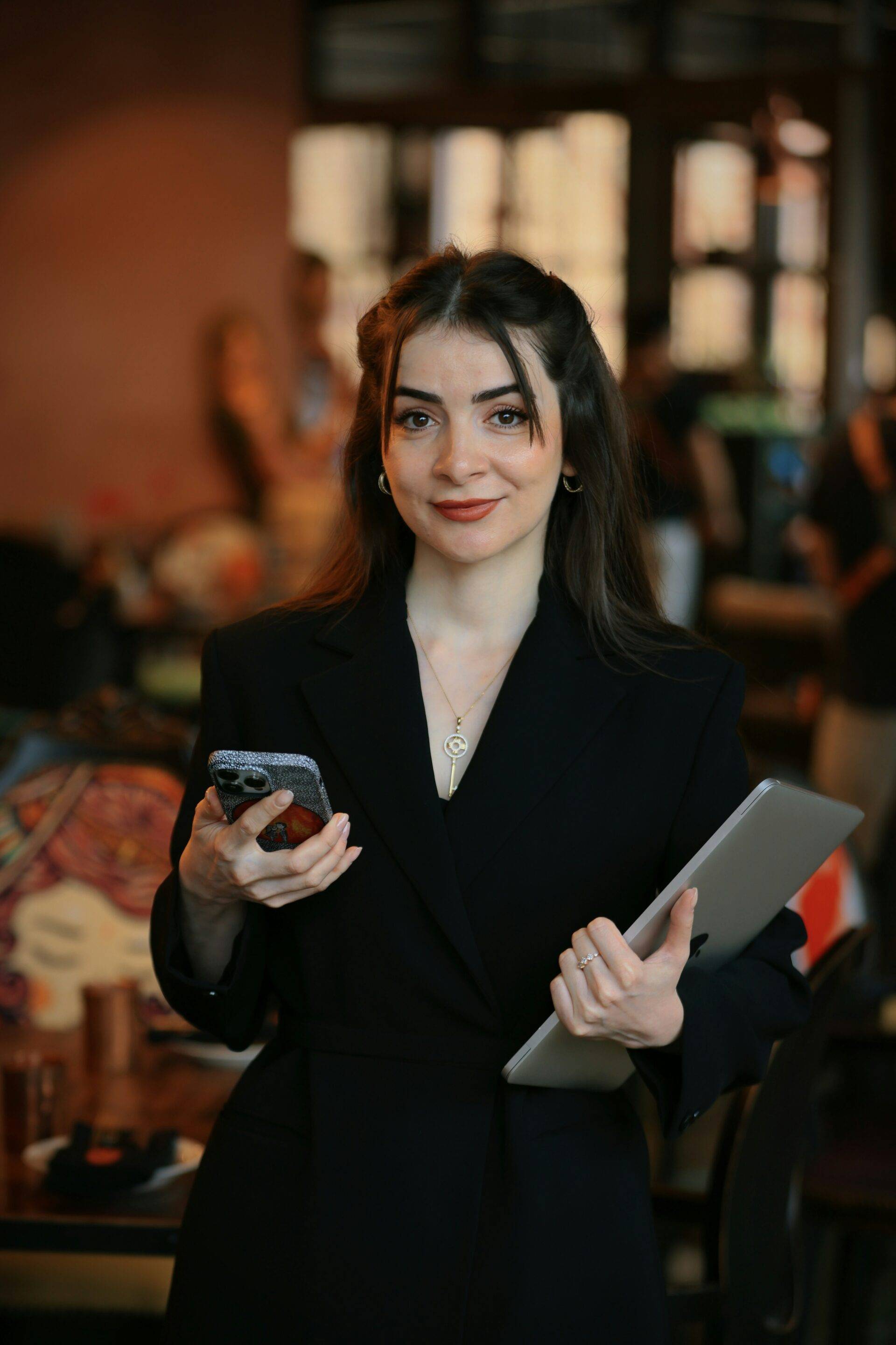 Business woman in black suit holding mobile phone and tablet.