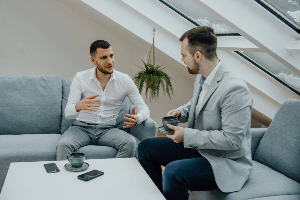 Two men sitting on a couch talking to each other