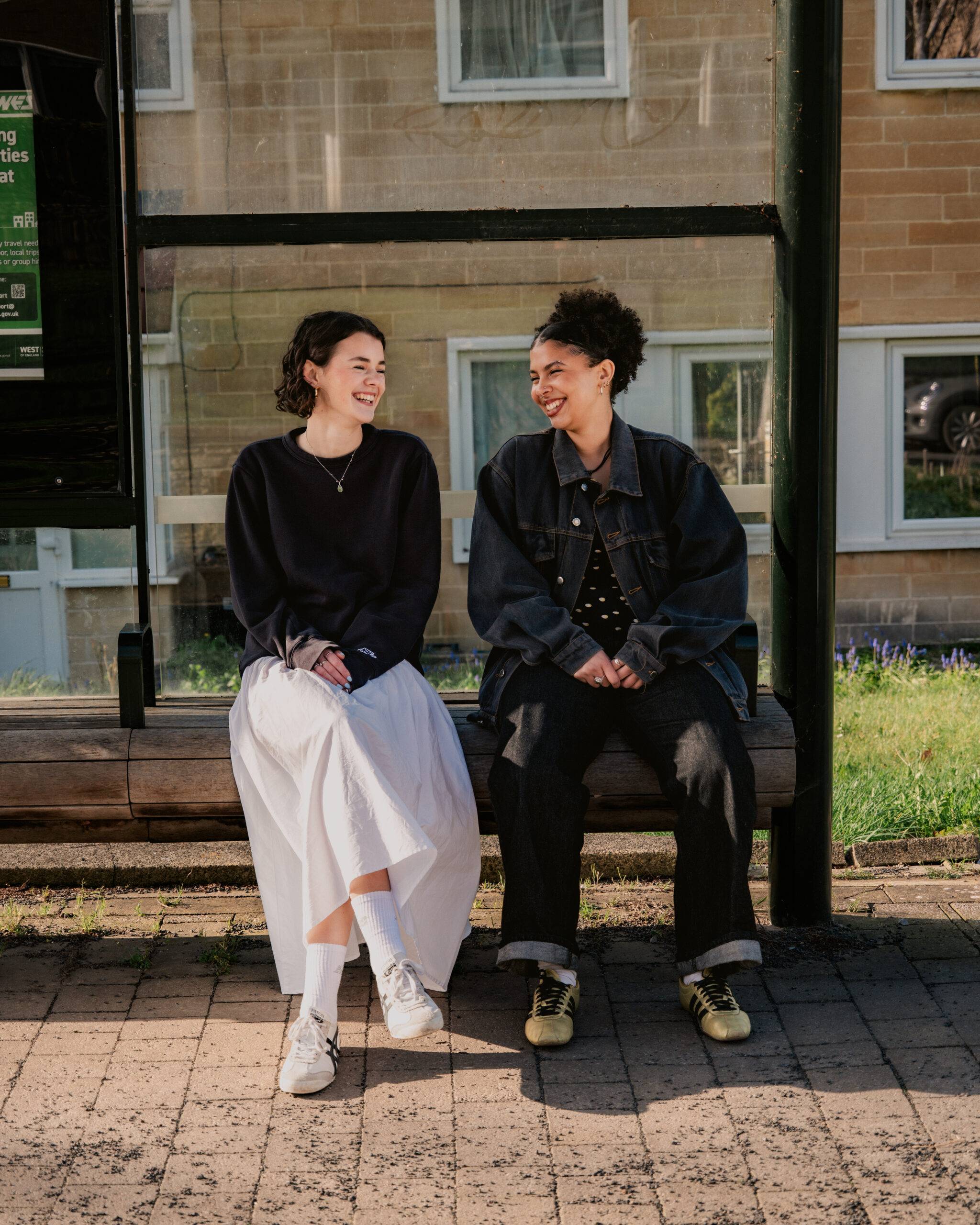 Two young women sat at bus stop
