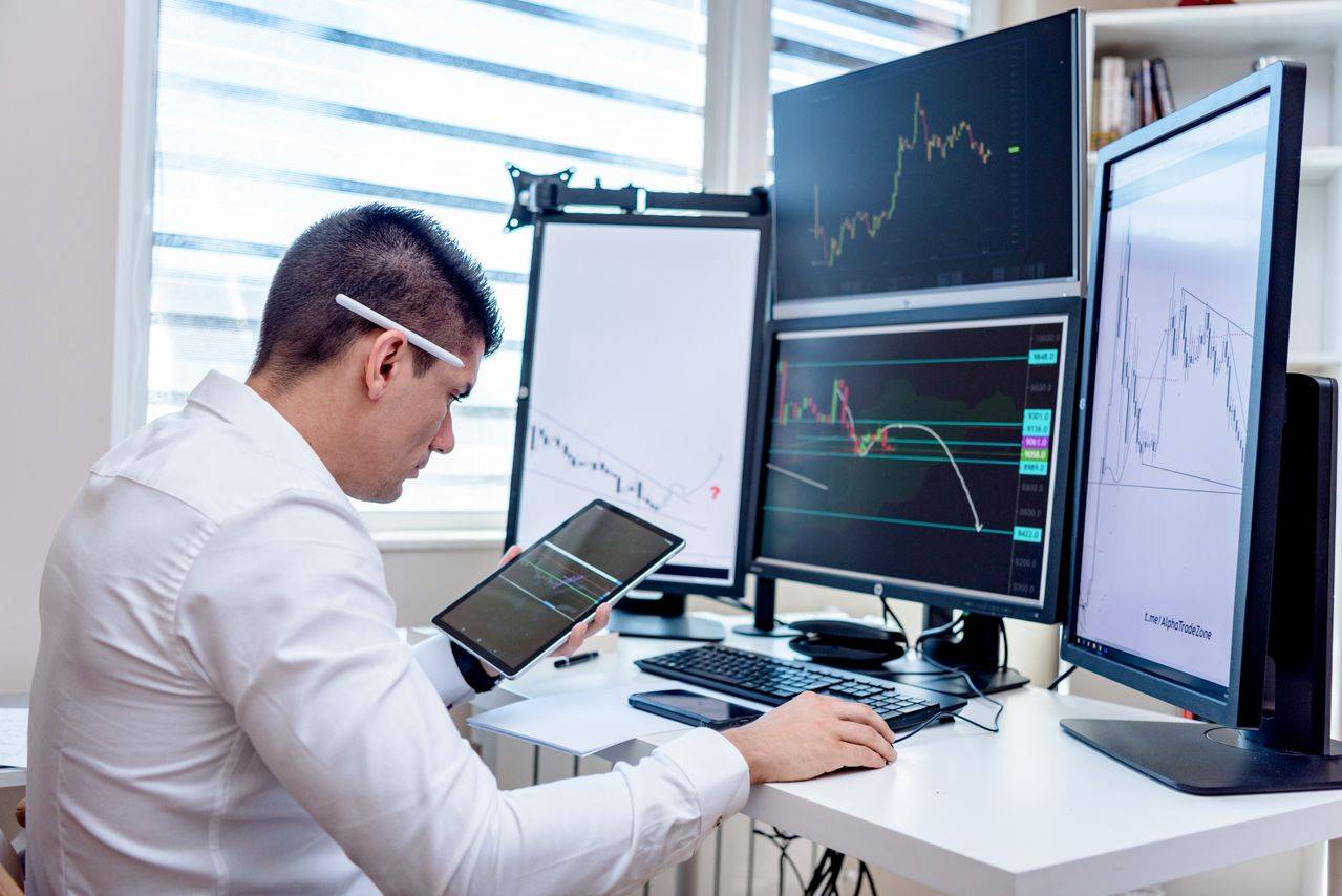 Person working at desk with lots of computer screens. 
